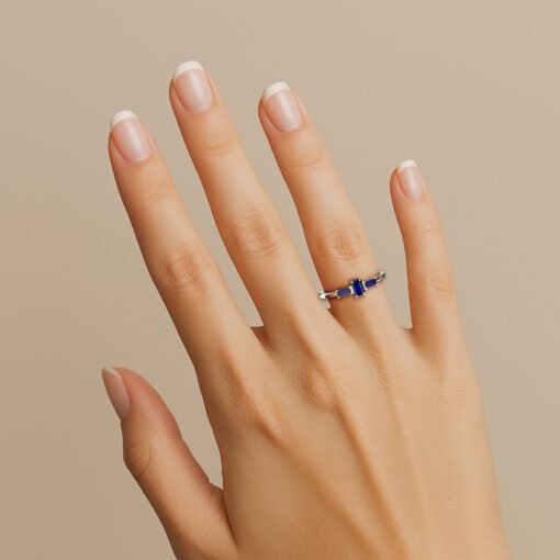 Mão vestindo o Anel de formatura Tríade em ouro branco 18k, com três safiras, para os cursos de administração engenharia, psicologia, entre vários outros